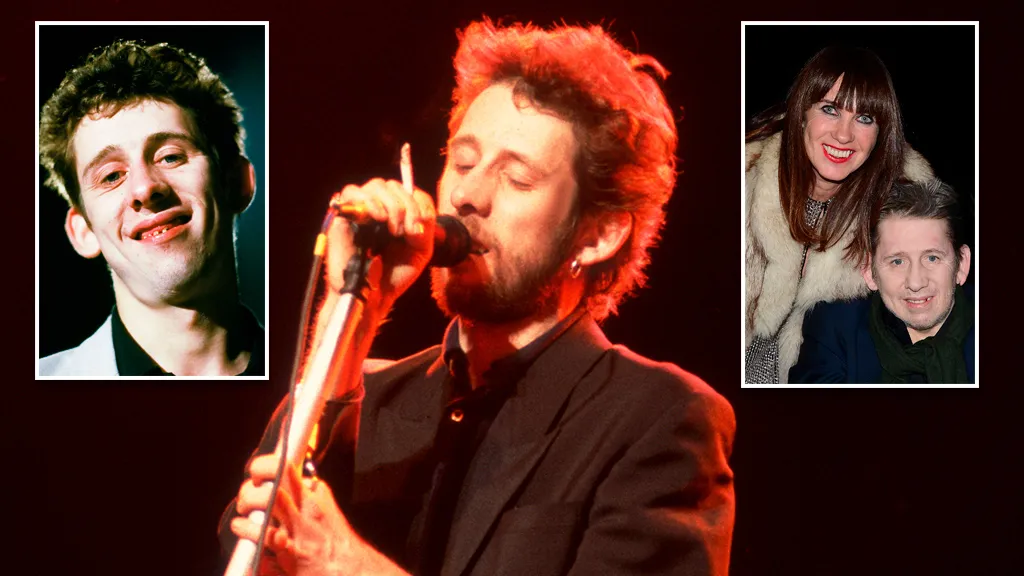 Shane MacGowan performing on stage with a microphone and guitar.